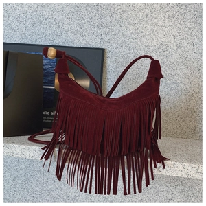 Détail du sac croissant en daim bordeaux avec franges étagées et perle en bois ronde
