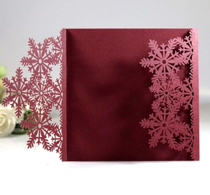 Detail of burgundy laser-cut snowflake invitation with metallic glitter cardstock
