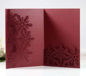 Detail of burgundy laser-cut snowflake invitation with pearlescent finish and floral accent