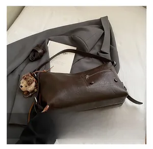 Detail showing deep brown faux leather crossbody bag with side zipper and plush bear charm