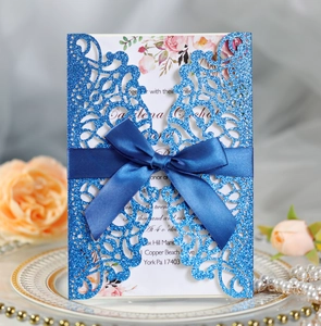 Royal blue glitter laser-cut invitation with navy satin bow and floral inner card