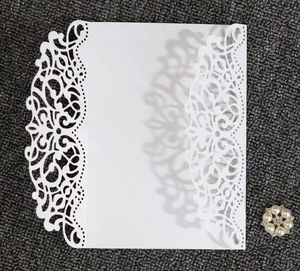 Detail of laser-cut white wedding invitation featuring intricate floral hollow patterns