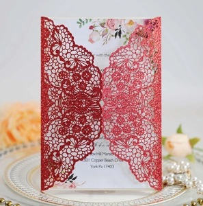 Detail of red glitter laser-cut wedding invitation with white floral inner card and lace cover