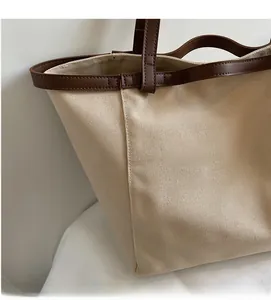 Detail of canvas tote bag showing the natural fabric texture and brown leather strap