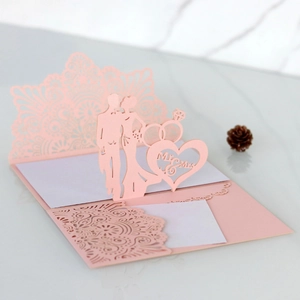 Macro detail of laser-cut wedding invitation featuring 3D Mr & Mrs pink floral paper design
