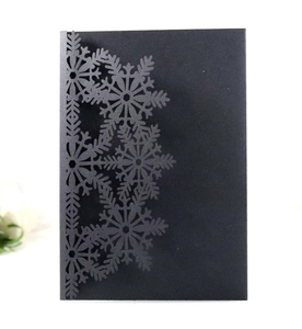 Detail of laser-cut snowflake design on dark green cardstock holiday invitation