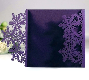 Close-up of laser-cut snowflake hollow patterns on a deep purple square invitation card