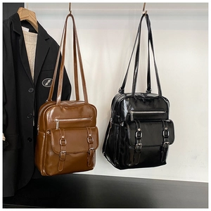 Detail view of vintage oil wax leather backpacks in brown and black with metal buckles
