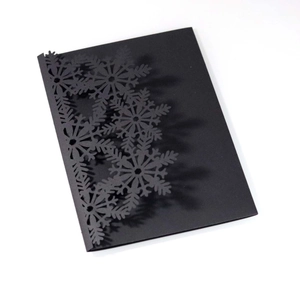 Macro detail of laser-cut snowflake design on premium black cardstock invitation