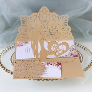 Detail of laser-cut gold wedding invitation with Mr & Mrs silhouette on glass tray