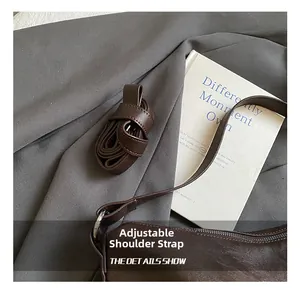 Detail of adjustable leather shoulder strap with silver buckle on dark brown bag