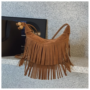 Détail d'un sac hobo en daim marron avec des franges étagées et des perles décoratives en bois