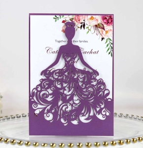 Detail of laser-cut purple gown invitation card with floral inner sheet on glass tray
