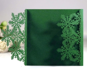Macro detail of laser-cut snowflake patterns on a dark green invitation card cover