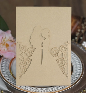 Close-up of laser-cut hollow silhouette of a couple on champagne gold wedding invitation