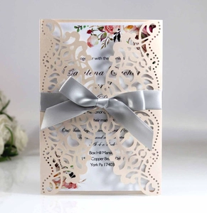 Macro detail of laser-cut wedding invitation with satin bow and floral insert card