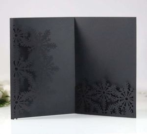 Detailed close-up of a laser-cut black card featuring intricate snowflake patterns