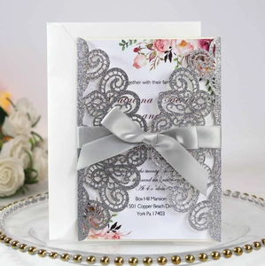 Détail de l'invitation de mariage argentée découpée au laser avec ruban et carte fleurie