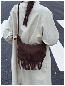 Detail of dark brown suede tassel bag with wooden bead accent and retro boho styling