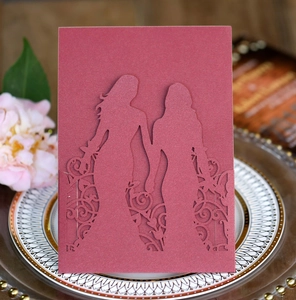 Detail of laser-cut burgundy wedding invitation featuring two female silhouettes and floral art