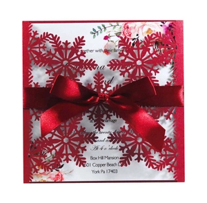 Detail of red laser-cut snowflake wedding invitation with a satin ribbon and floral insert