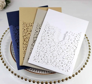 Detailed laser cut wedding invitation cards in navy, kraft, grey and white on a decorative tray