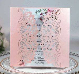 Detail of pink laser-cut lace invitation with elegant butterfly pattern and inner card