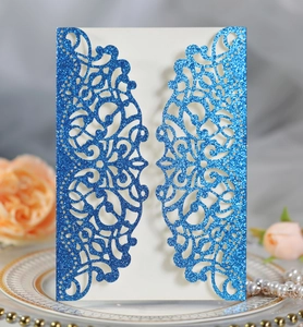 Close-up of laser-cut glitter blue invitation with intricate floral hollow pattern
