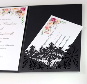 Close-up of laser-cut snowflake design on dark invitation card with floral details
