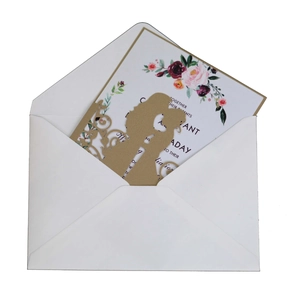 Detail of laser-cut gold wedding invitation with couple silhouette and floral inner card