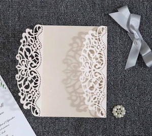 Detail of laser-cut lace floral pattern on ivory tri-fold wedding invitation cover