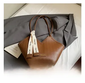 Detail of brown herringbone textured tote bag with chic V-cut and decorative ribbon
