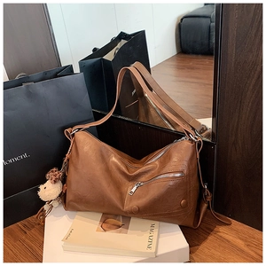 Brown leather underarm bag detail featuring a zipper pocket and cute bear charm accessory
