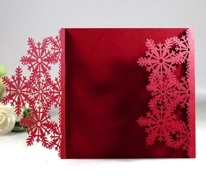 Detailed laser-cut snowflake patterns on a deep red metallic textured invitation card