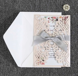 Detail of laser cut lace wedding invitation with pink pearl paper and satin bow