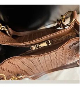 Detail of smooth metal zipper and woven texture on brown synthetic leather tote bag
