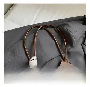 Detail of brown leather tote bag with V-shaped perforations and decorative silk ribbon