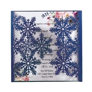 Detail of laser-cut snowflake wedding invitation with blue cover and floral inner page