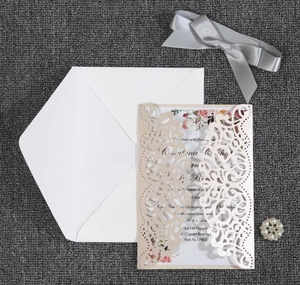 Detailed laser-cut beige wedding invitation set with floral card, ribbon and pearl charm