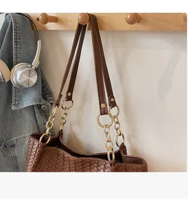 Detail of caramel brown woven leather tote with golden chain strap and textured pattern