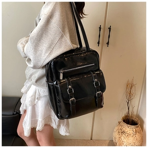 Side view of a vintage glossy black faux leather backpack worn by a model in a cozy setting