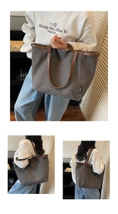 Detail of large canvas tote bag with brown leather handles and brand label on grey fabric