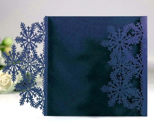 Detail of laser-cut snowflake patterns on navy blue paper wedding invitations