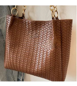 Detail of brown woven tote bag with metallic rings and Fashion & Bag logo plaque