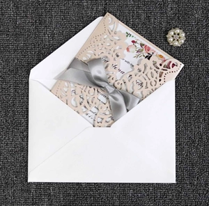 Detailed laser-cut champagne wedding invitation set with floral inner card and grey ribbon