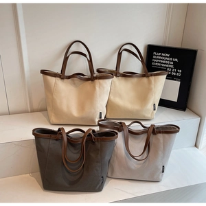 Four minimalist large canvas tote bags with leather handles on marble display