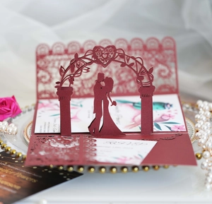 Detail of burgundy laser-cut 3D wedding invitation with couple silhouette and floral print