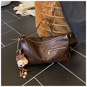 Detailed view of brown faux leather shoulder bag with zipper pocket and bear charm