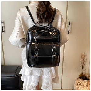 Close-up of black glossy backpack with silver hardware buckles and front zipper pocket