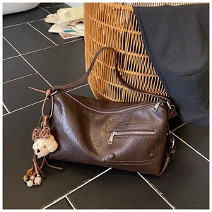 Detail of vintage oil wax leather shoulder bag with side plush bear and bead charms